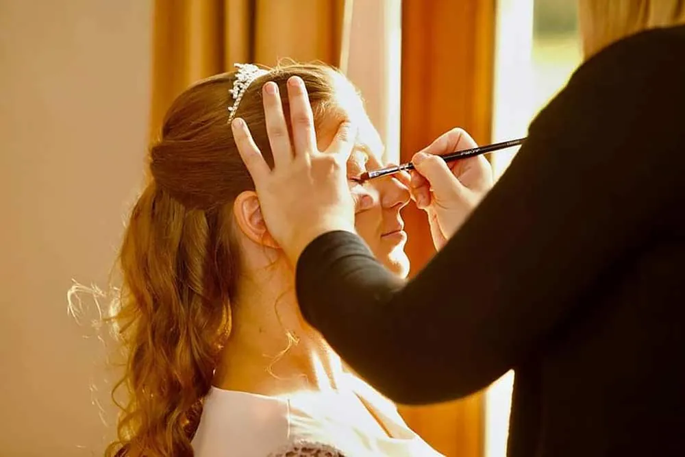 Make-up wordt aangebracht bij een bruid
