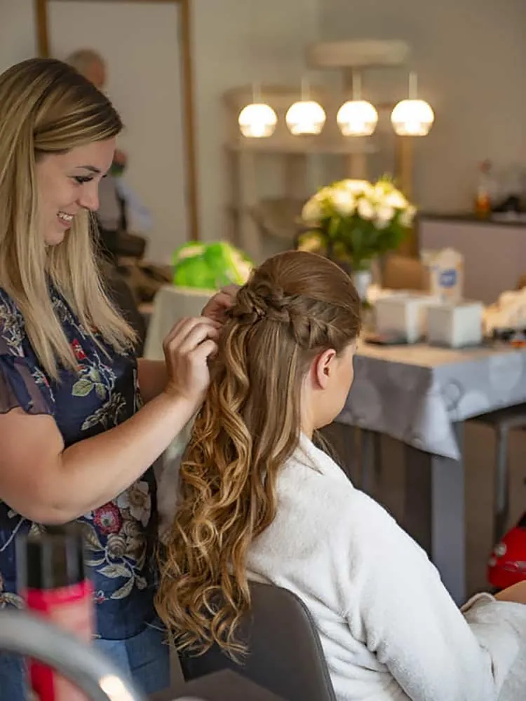 Mallaury werkt aan een kapsel met vlechten en krullen in het salon